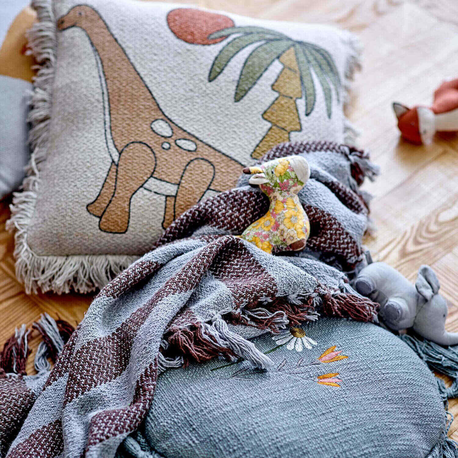 Graues Elefanten-Kuscheltier auf Decke mit buntem Muster und Stoffschal