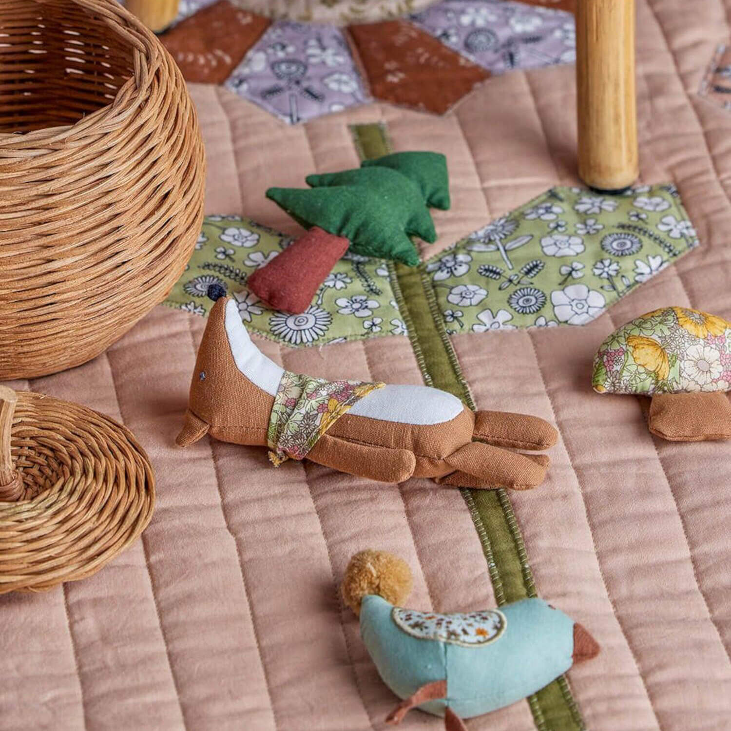Stoff-Spielzeugfiguren auf Patchworkdecke, grüne und braune Tiermotive