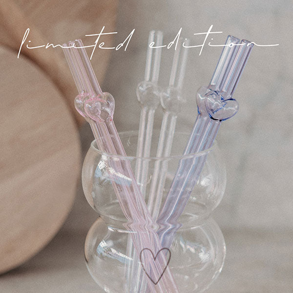 Glasstrohhalm-Set mit Herzaufsatz über einem Becher: rosa, flieder und transparent