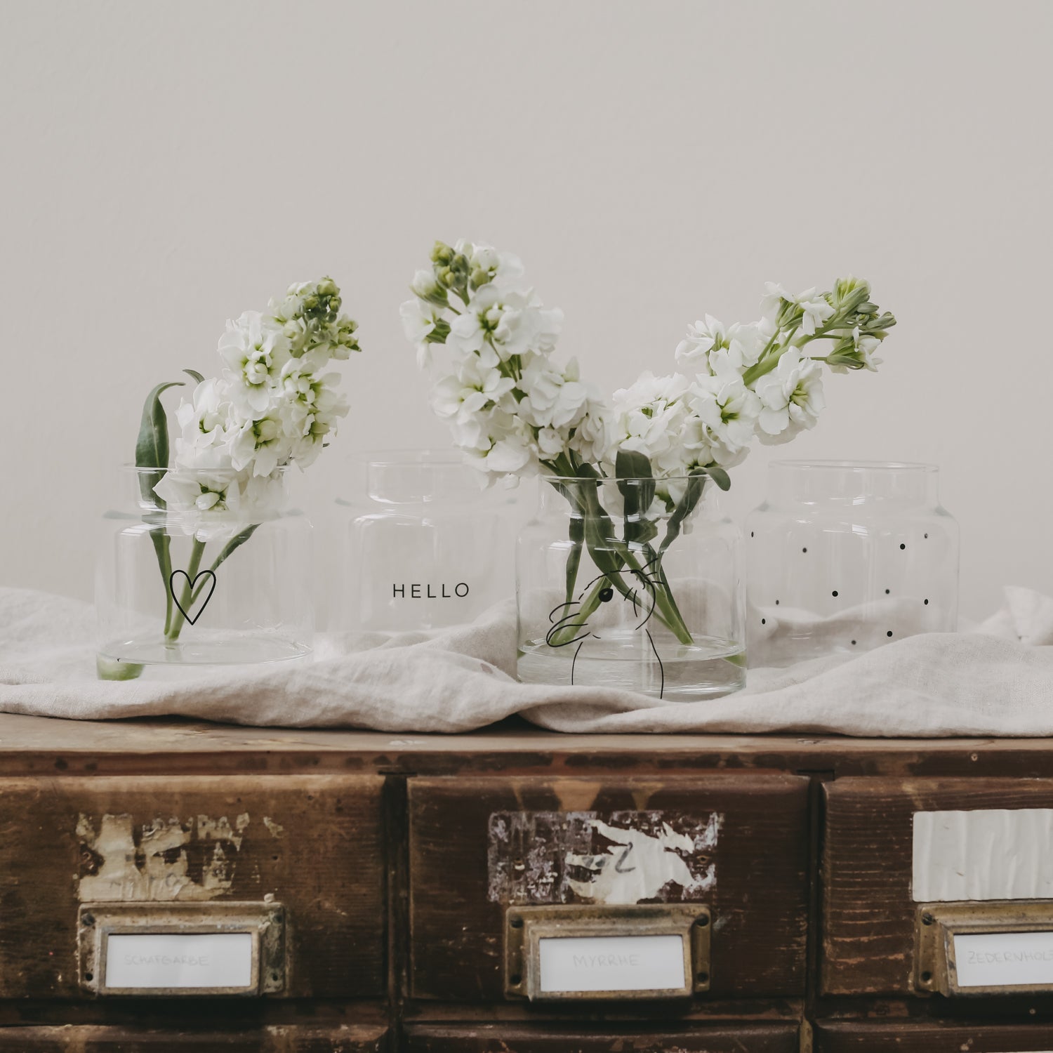 Set aus Glasvasen mit Herz-Aufdruck, dekoriert mit weißen Blüten