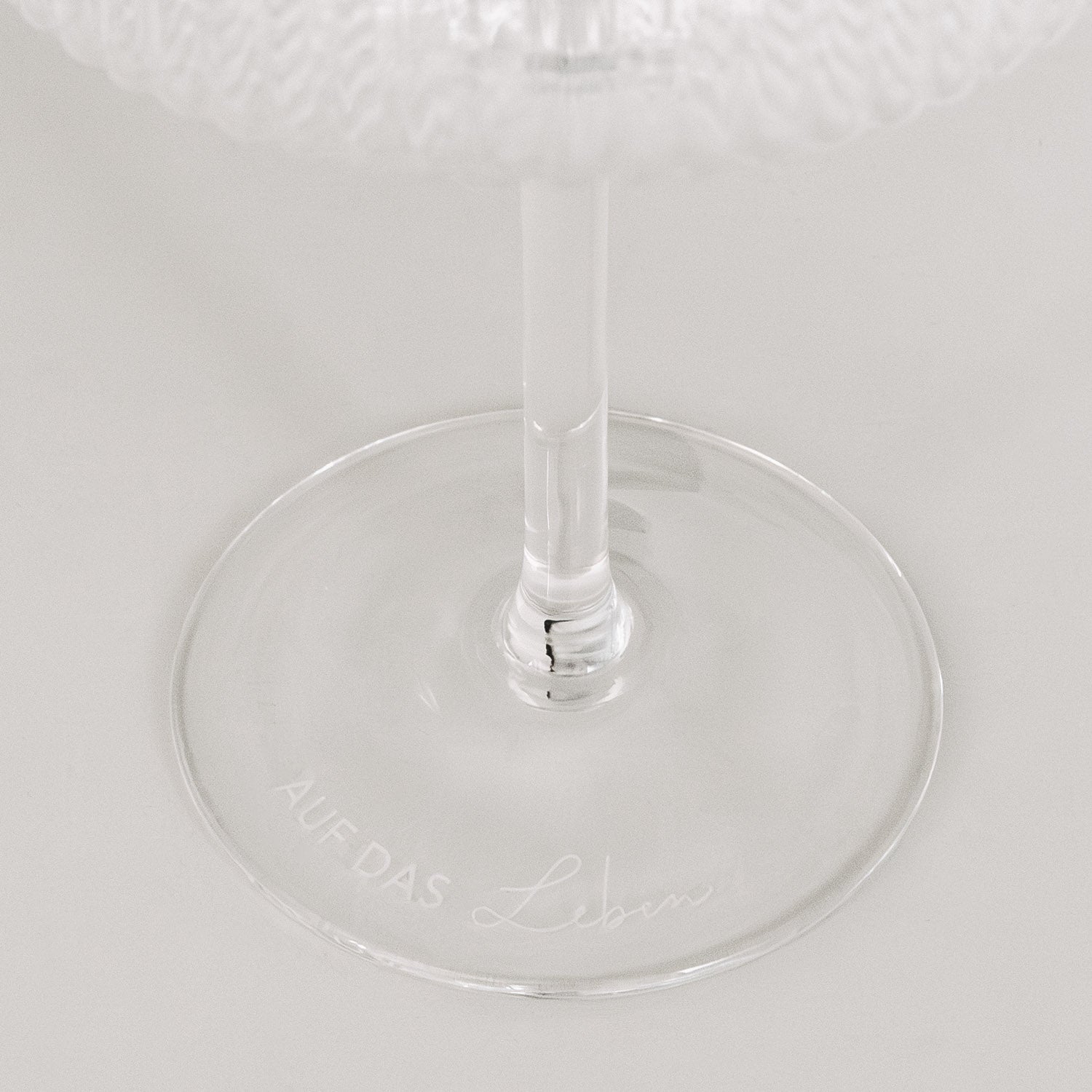 Champagnerglas: transparenter Fuß mit geprägter Aufschrift „AUF DAS LEBEN“