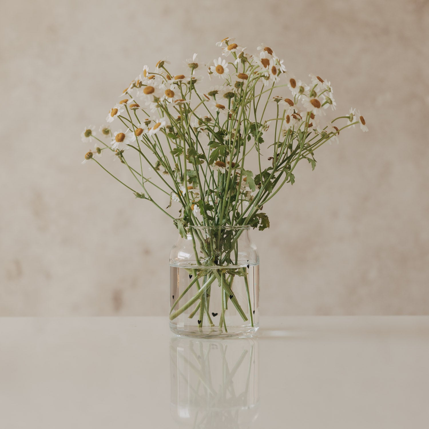 Vase aus klarem Glas mit Herz-Muster, mit gebundenem Blumenstrauß