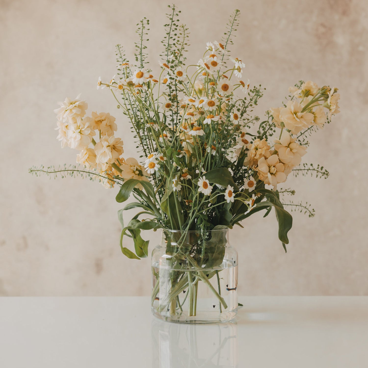 Glasvase mit Herzmotiven, mit Blumenstrauß gefüllt, zylindrische Form