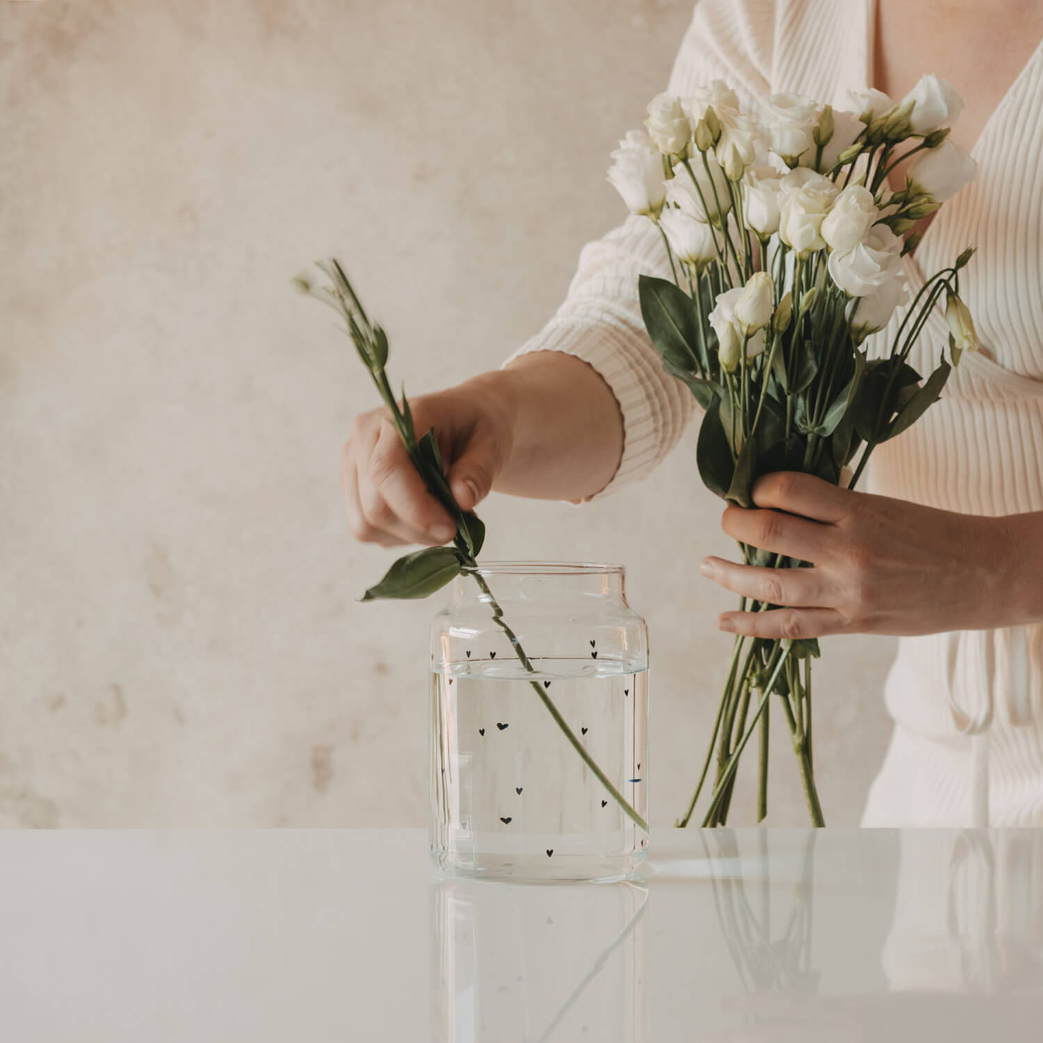 Große Glasvase mit Herzdekor, Blumen werden gerade hineingestellt