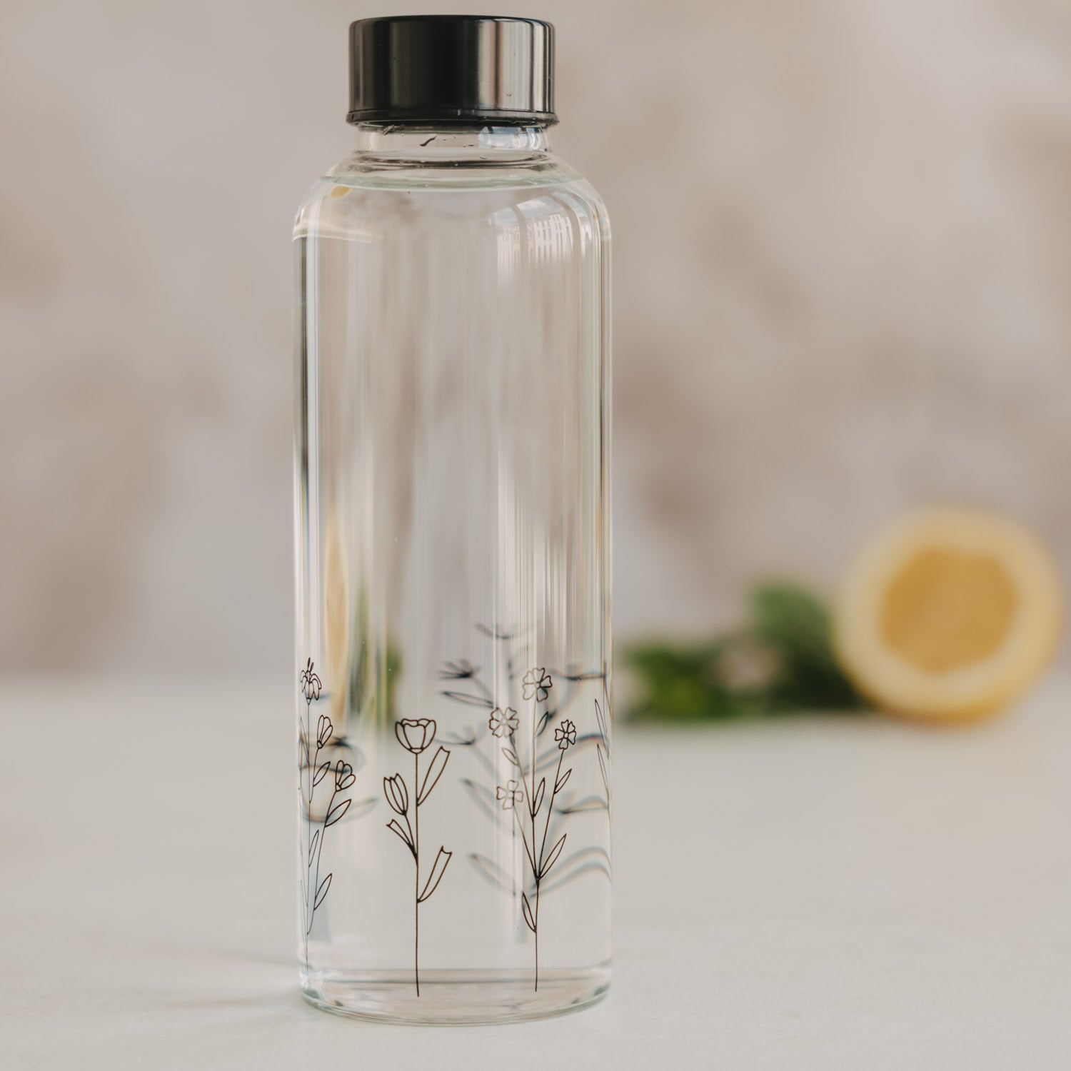 Transparente Trinkflasche 500 ml mit schwarzem Deckel und Blumenwiesen-Motiv vorne