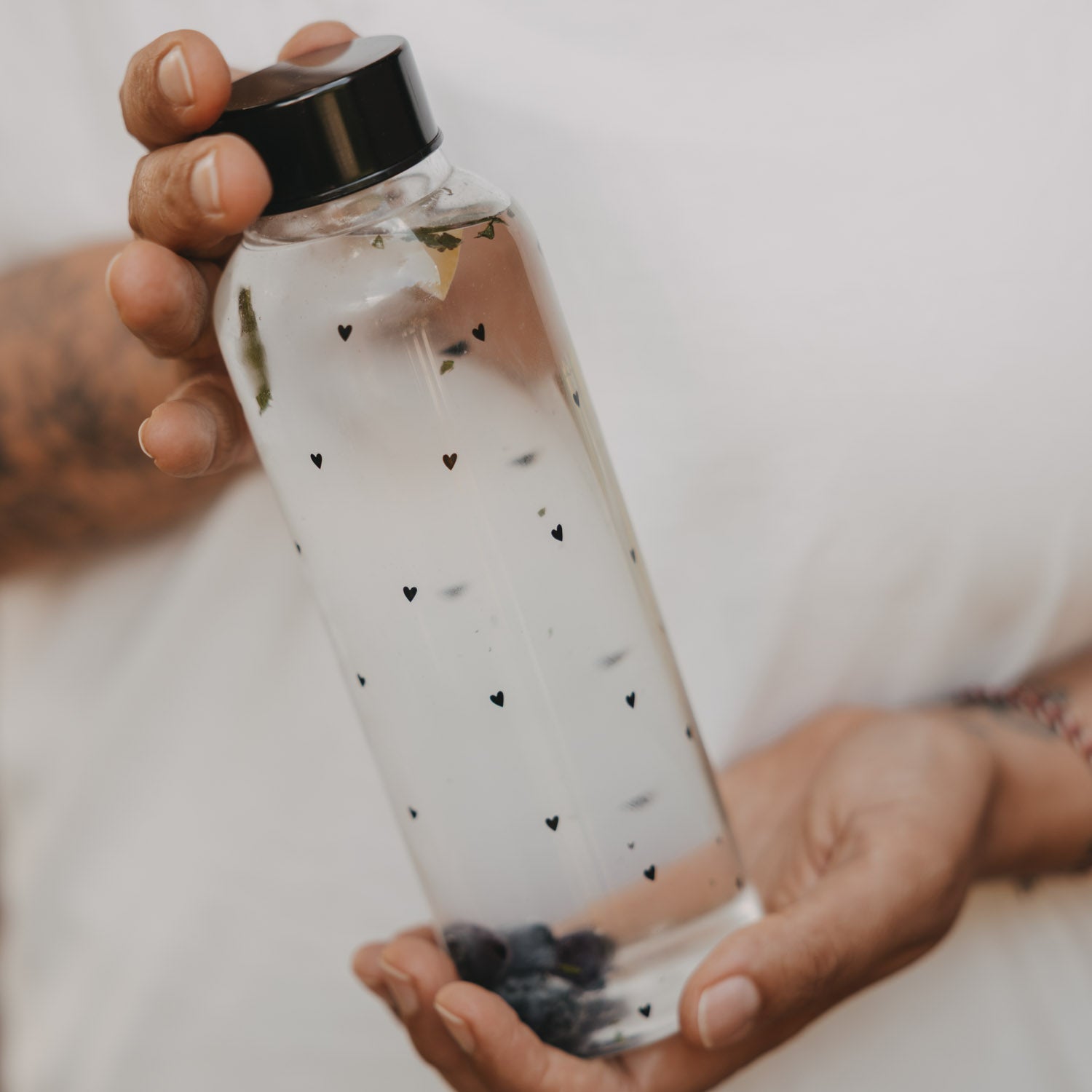 Transparente Trinkflasche mit Herzmuster und schwarzem Deckel