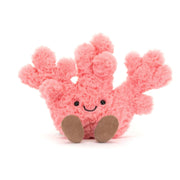 Kuscheltier Koralle, rosa Plüschtier mit lächelndem Gesicht, schwarzen Augen und braunen Beinen
