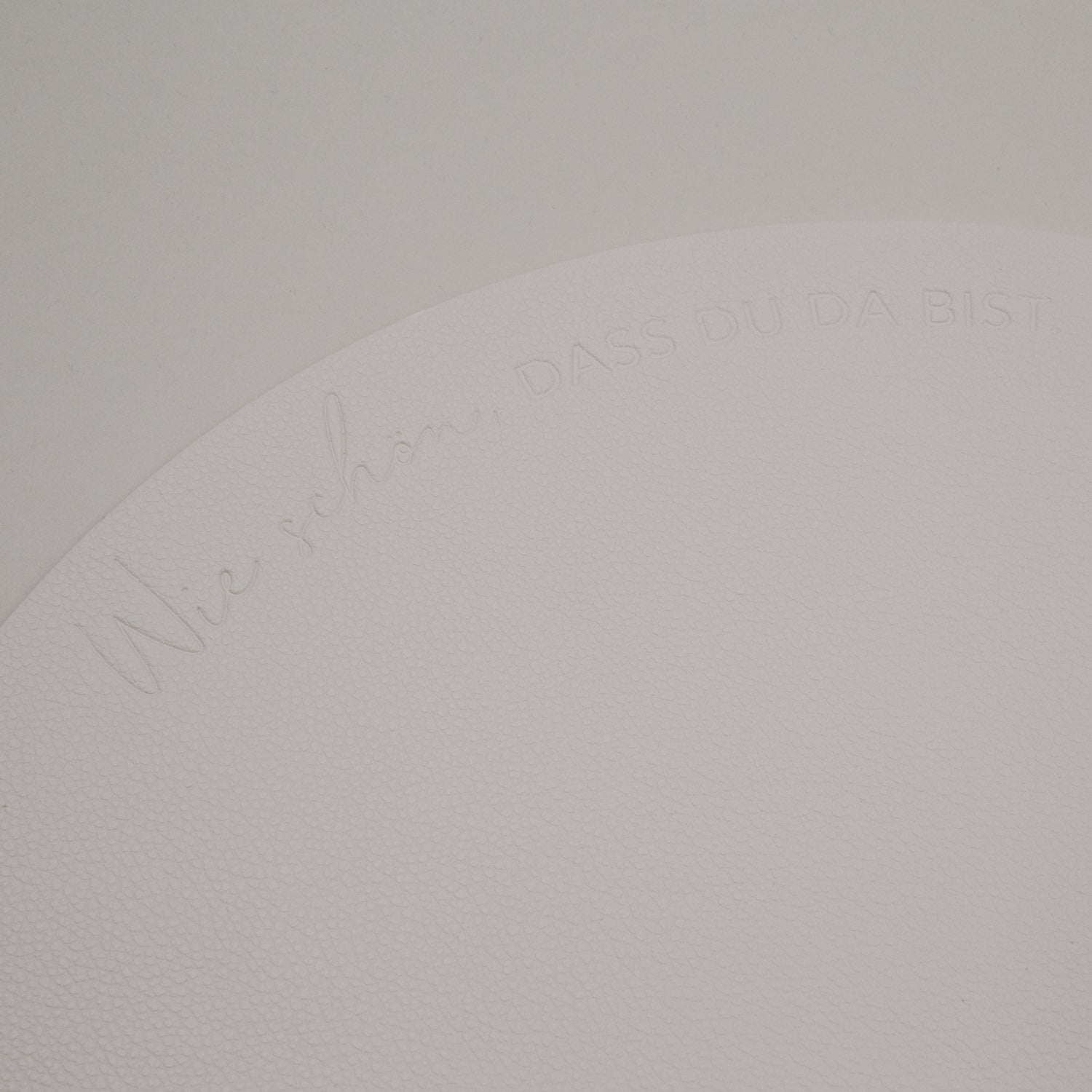 Detail der Prägung auf hellem Platzset, Schriftzug entlang der Rundung