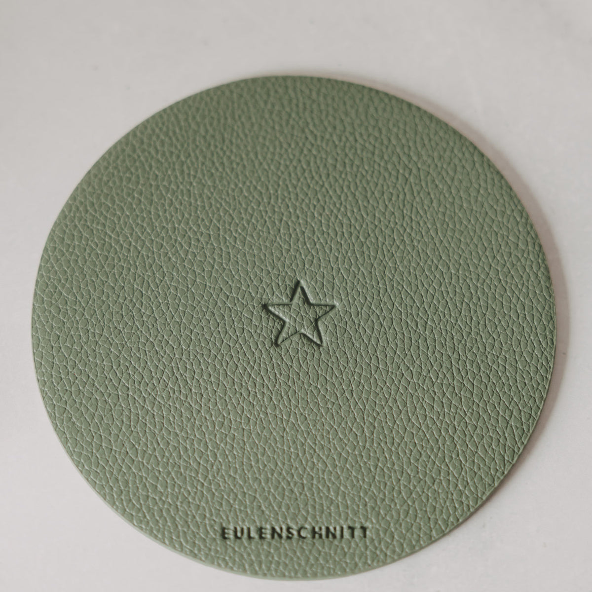 Grüne Untersetzer mit Stern-Prägung, rund, aus Kunstleder; Sicht auf Logo unten.
