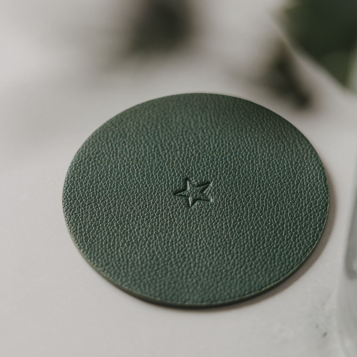 Grüner runder Untersetzer mit eingelassenem Sternmotiv in der Mitte.