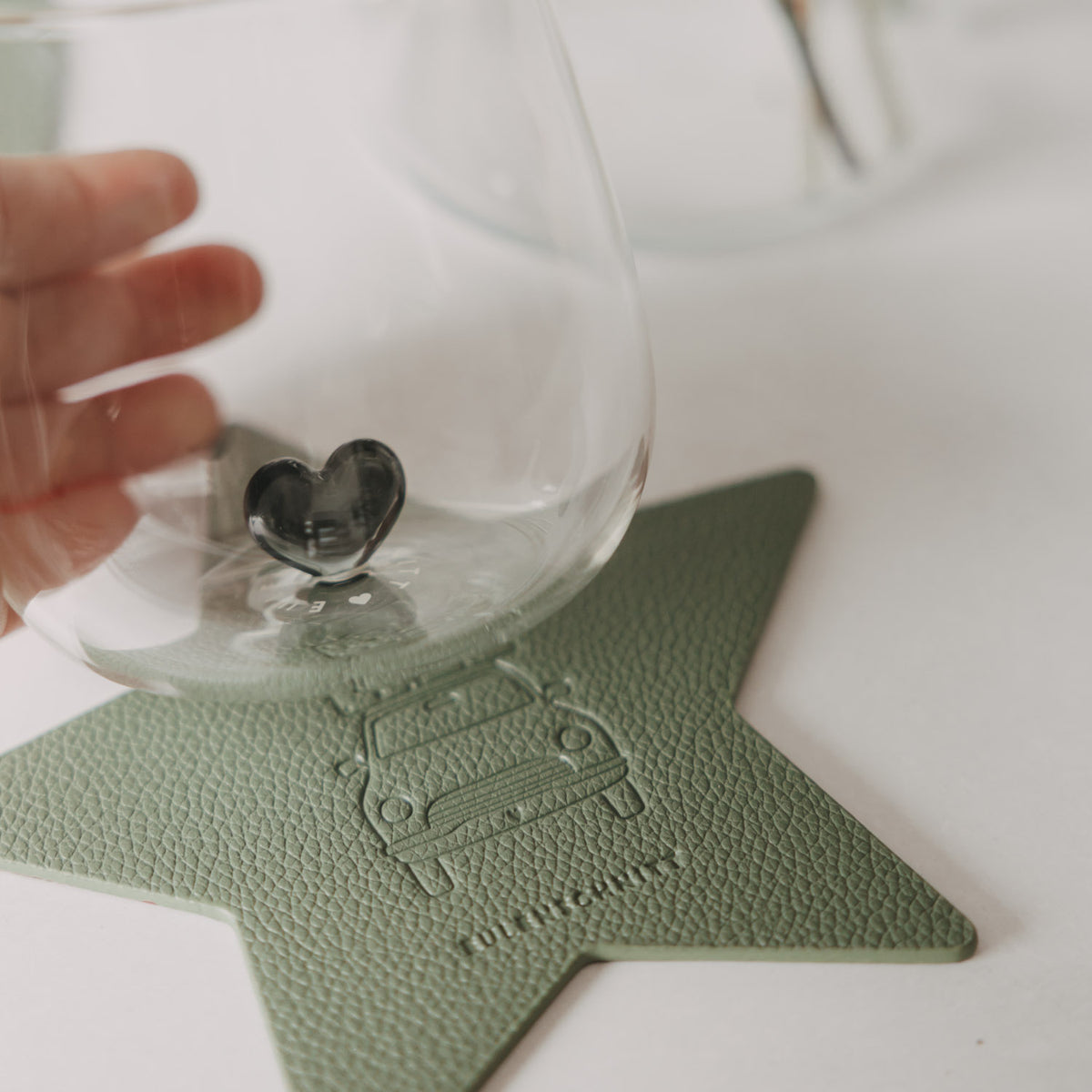 Grüner Stern-Untersetzer mit Wagenmotiv, unter einem Glas mit Herz