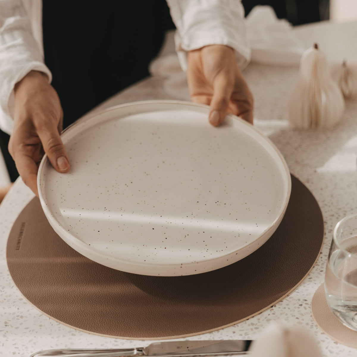 Rundes Platzset auf dem Tisch, beige Seite unter einer Servierschüssel.