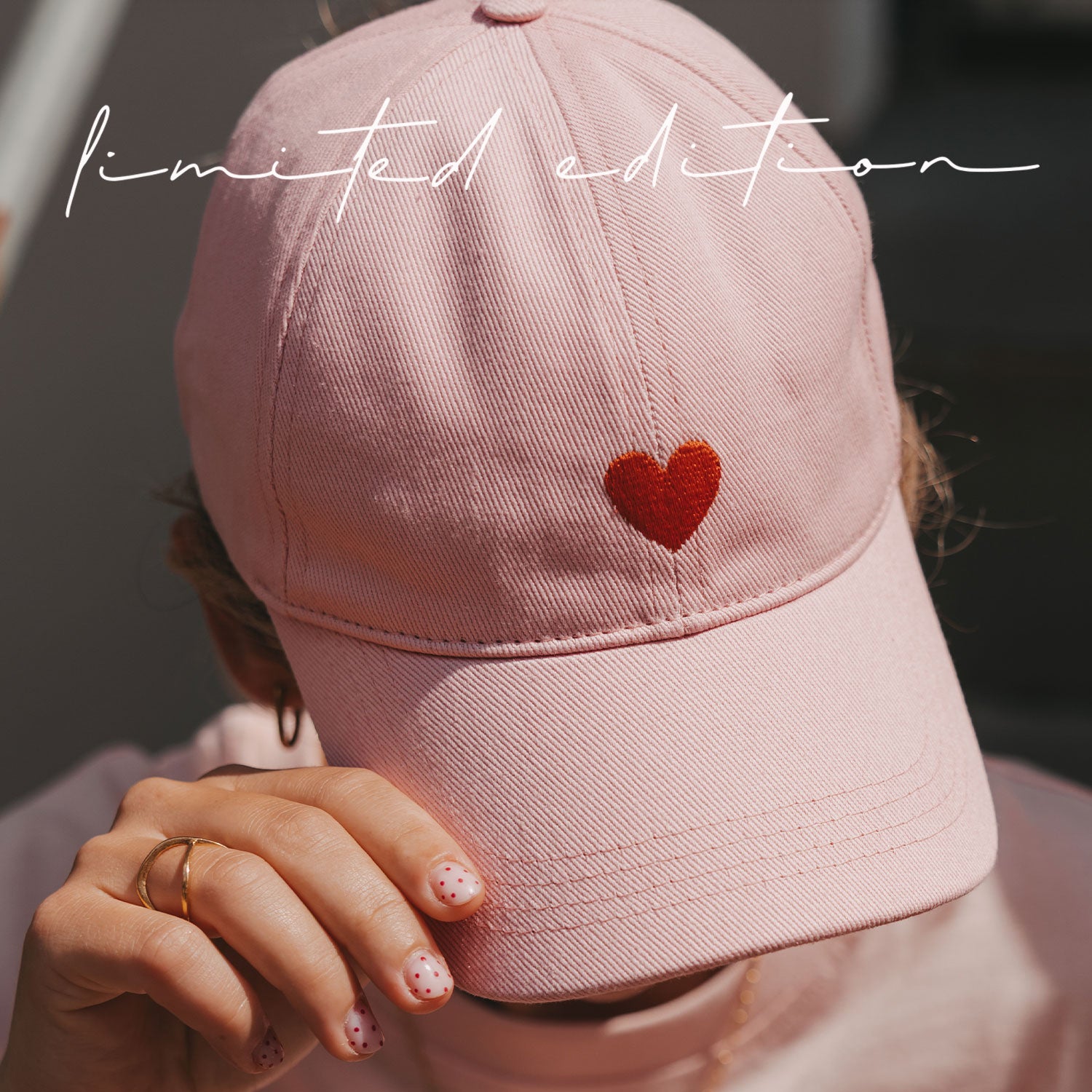 Rosa Basecap, vorderes rotes Herzstickmuster, seitliche Ansicht.