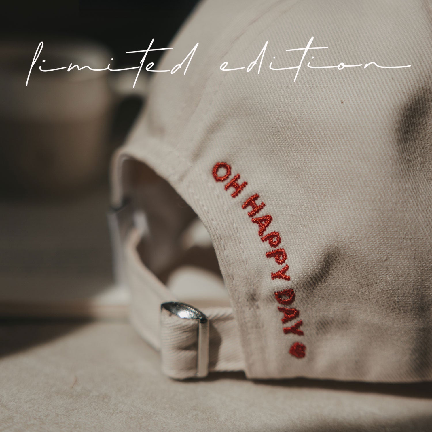 Beige Basecap im Detail: rote Stickschrift „Oh Happy Day“