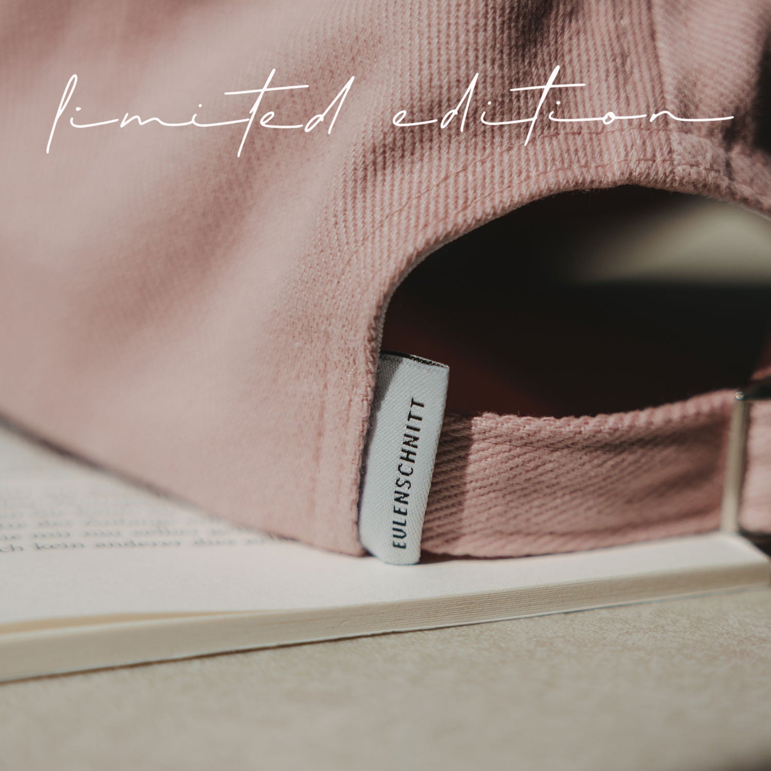 Rosa Basecap mit Innenetikett „EULENSCHNITT“ am Schaft.
