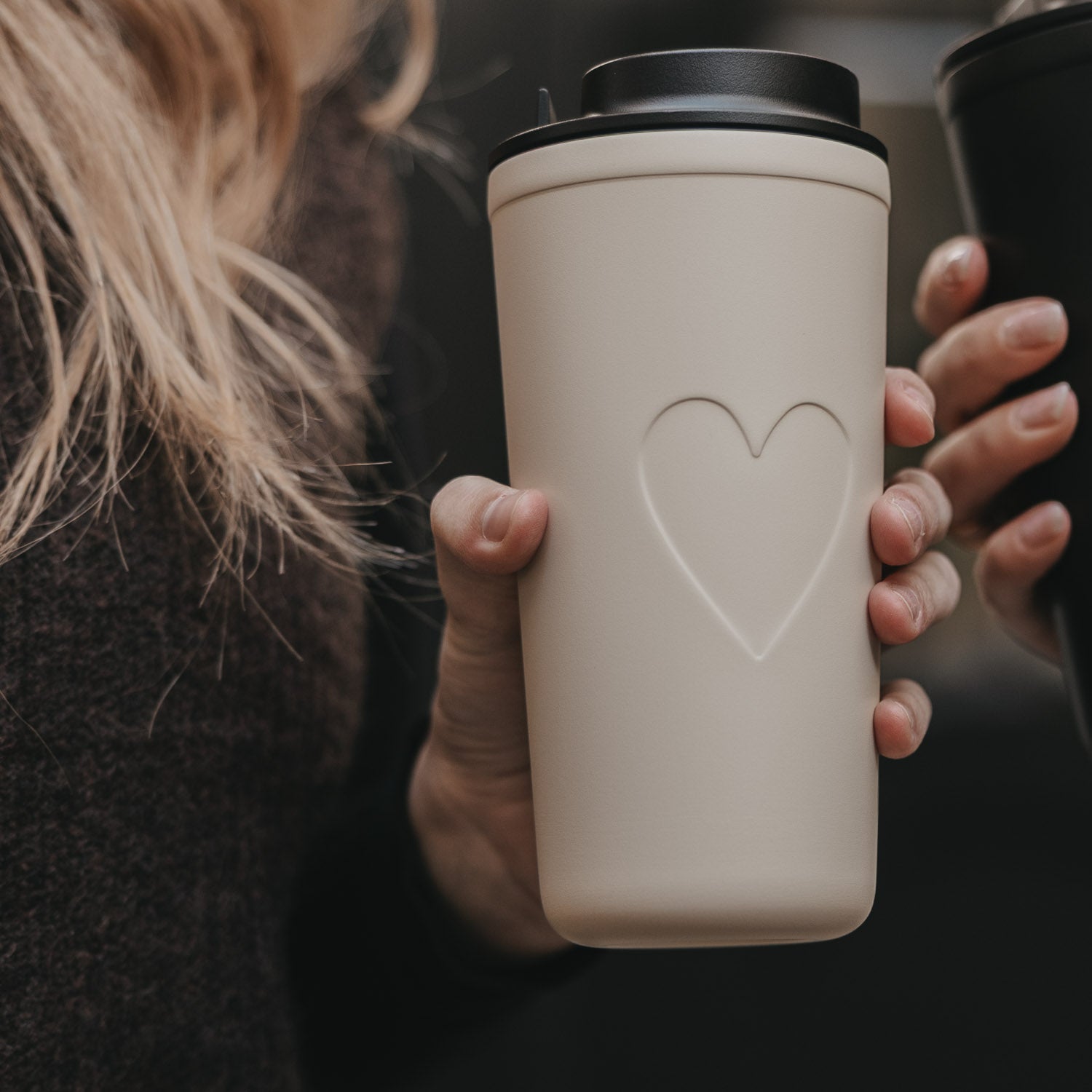 Cremefarbener To-go-Becher mit schwarzem Deckel und Herzprägung, frontal