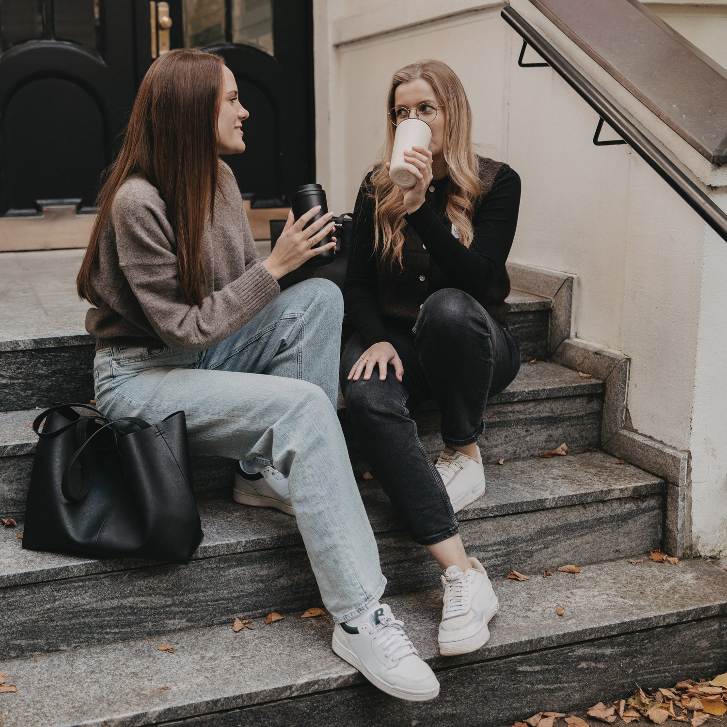 Cremefarbener To-go-Becher mit schwarzem Deckel und Herzprägung in der Hand