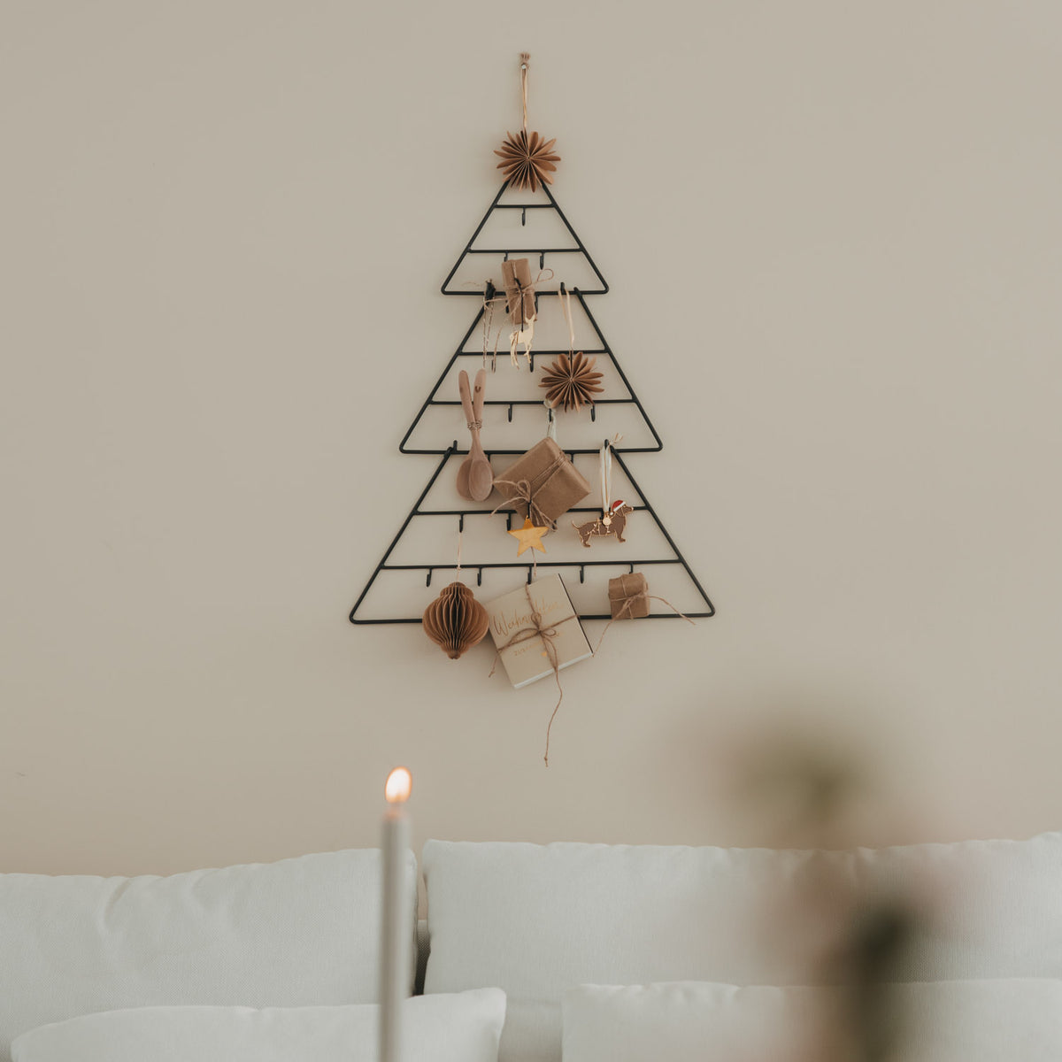 Tannenförmiger Adventskalender mit Geschenken und Holzdekoration, mit Kerze im Vordergrund