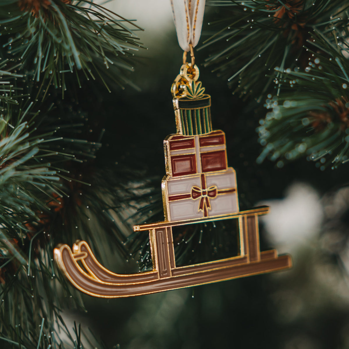 Goldener Schlitten-Baumschmuck auf Kufen, mit Geschenkboxen und Schleife
