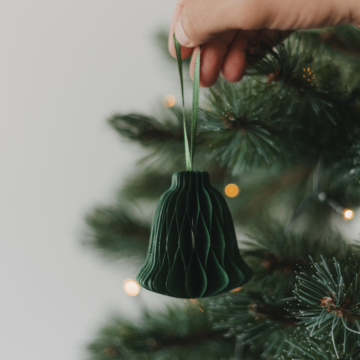Dunkelgrüner Papieranhänger Glocke mit Schlaufe, von Hand am Weihnachtsbaum aufgehängt