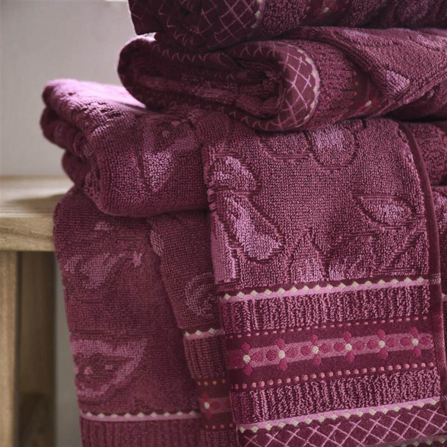 Handtuch in dunklem Pink mit floraler Jacquardstruktur, Streifenbordüre und Karomuster