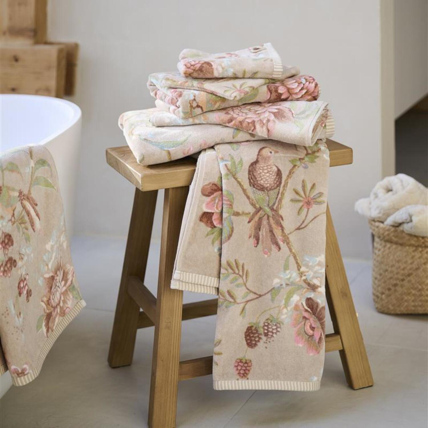 Tuch mit Blumenmuster, gefaltete Lappen auf Holzschemel, beiger Untergrund