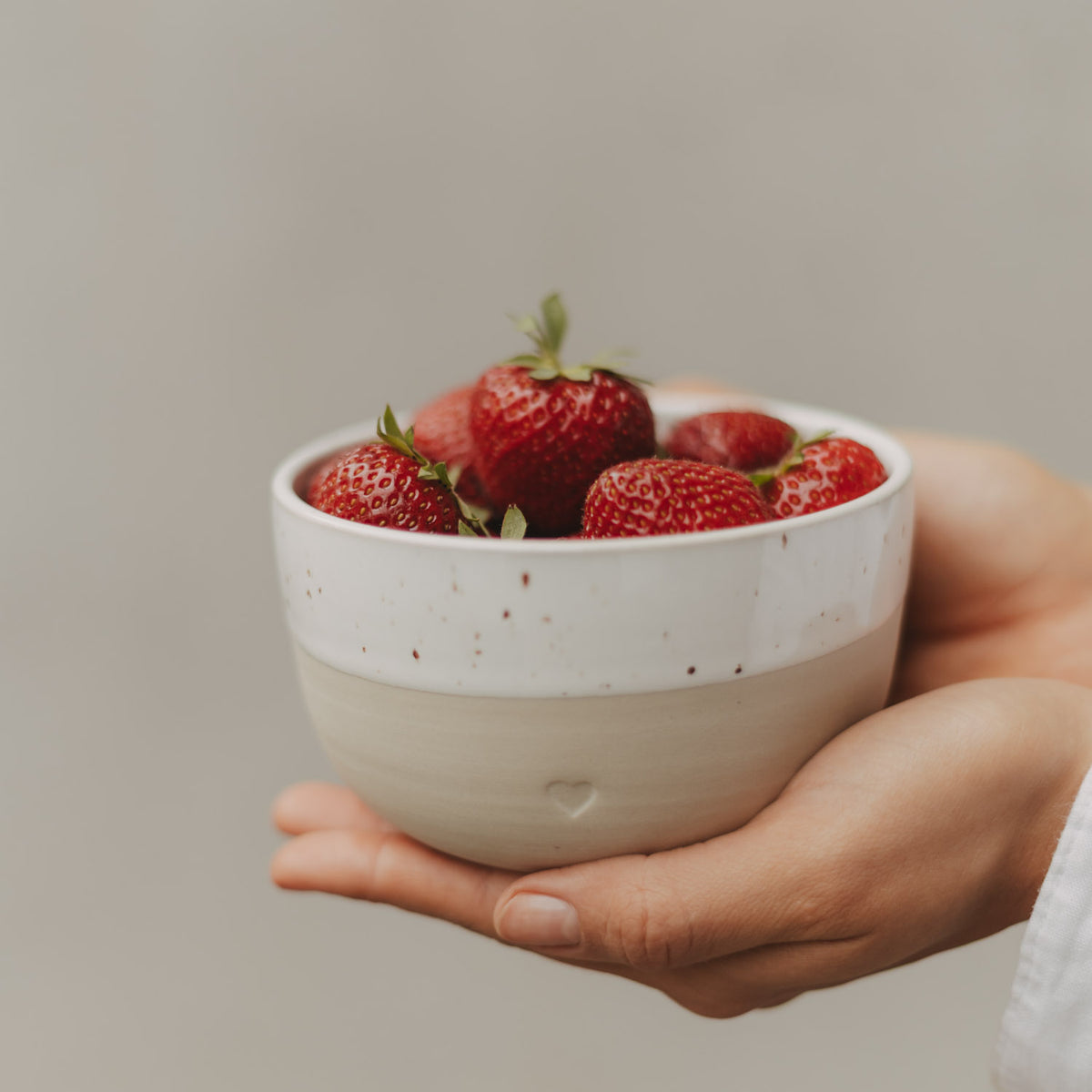 Herz-Schüssel mit Sprenkeln, weiß/cremefarben, gefüllt mit Erdbeeren, von Händen gehalten