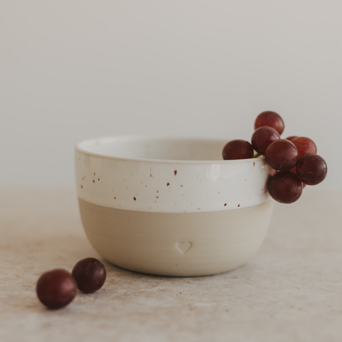 Herz-Schüssel mit Sprenkeln, weiß/cremefarben, mit roten Beeren daneben
