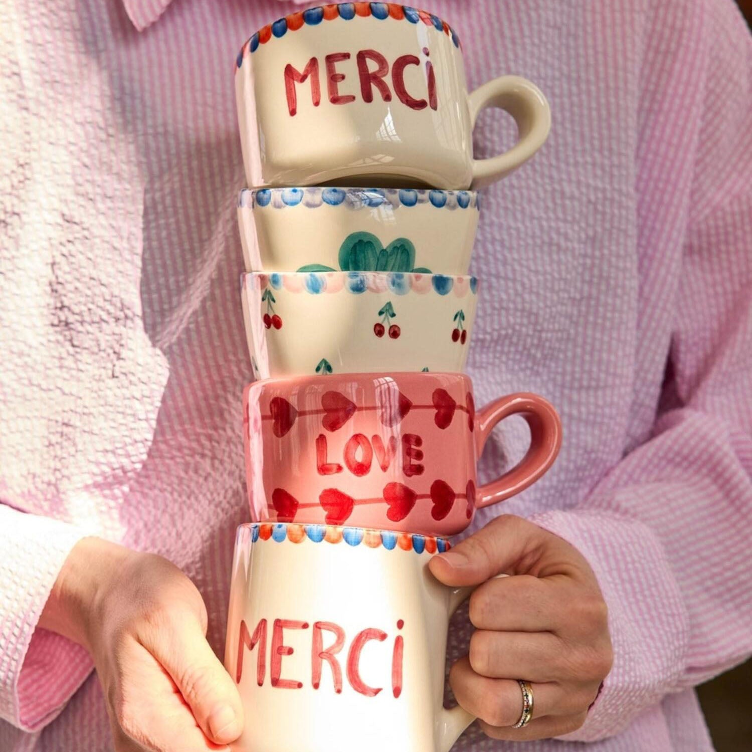Keramiktasse mit Schriftzug „Merci“ und Kleeblattdekor, weiß mit farbigen Mustern