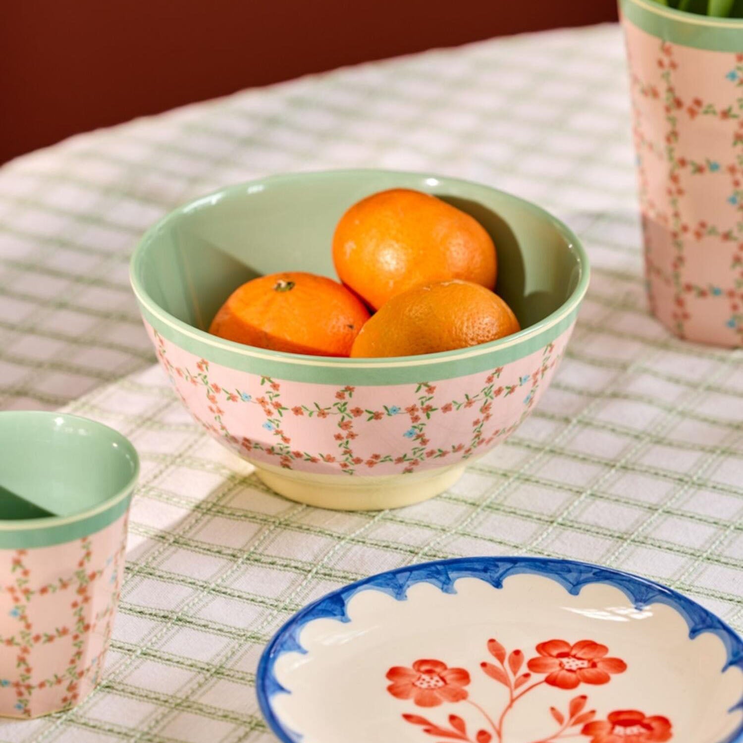 Melaminschale mit Blumenmuster und grünem Rand, gefüllt mit drei Orangen