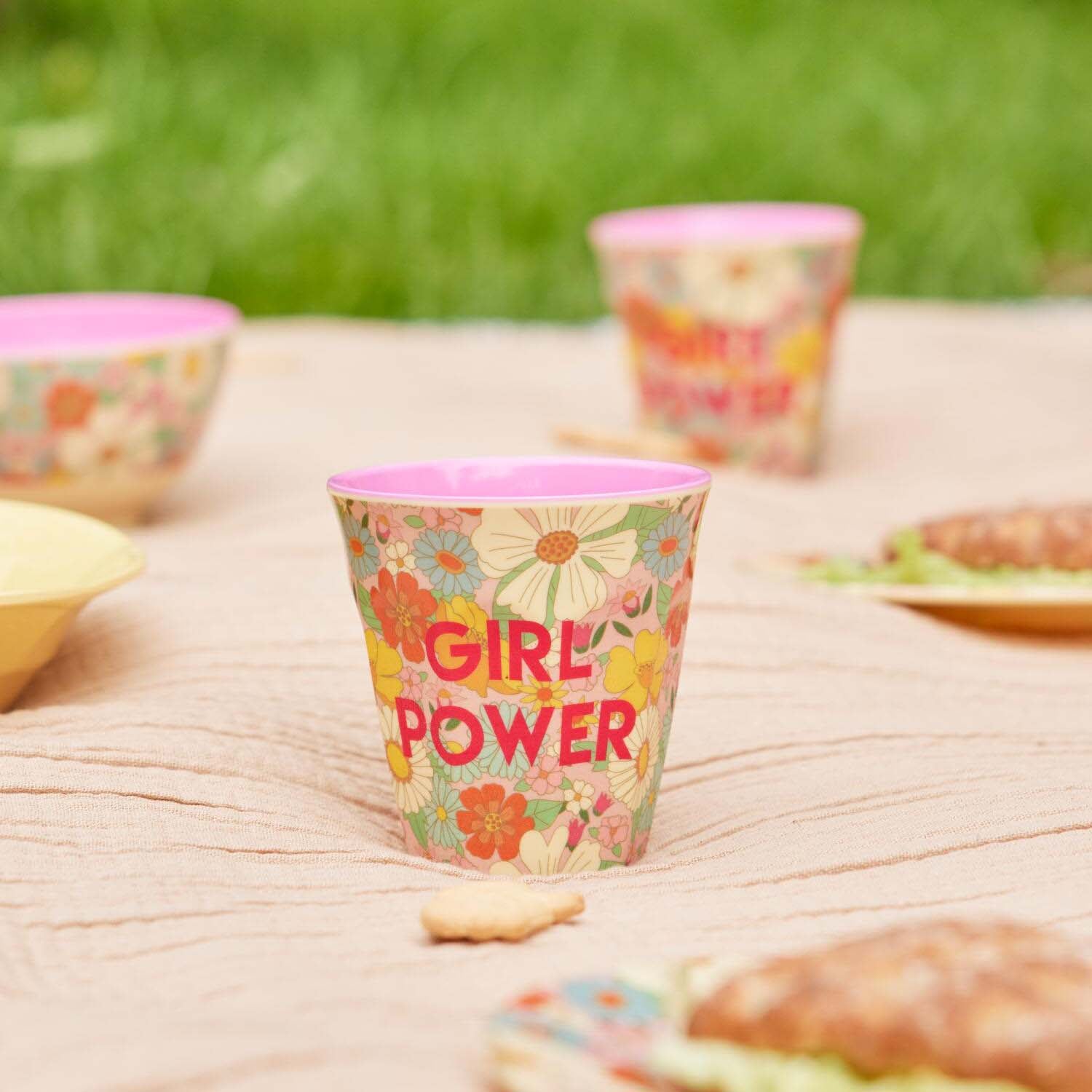 Melaminbecher „Girl Power“ mit buntem Blumenmuster und lila Rand auf hellem Tisch