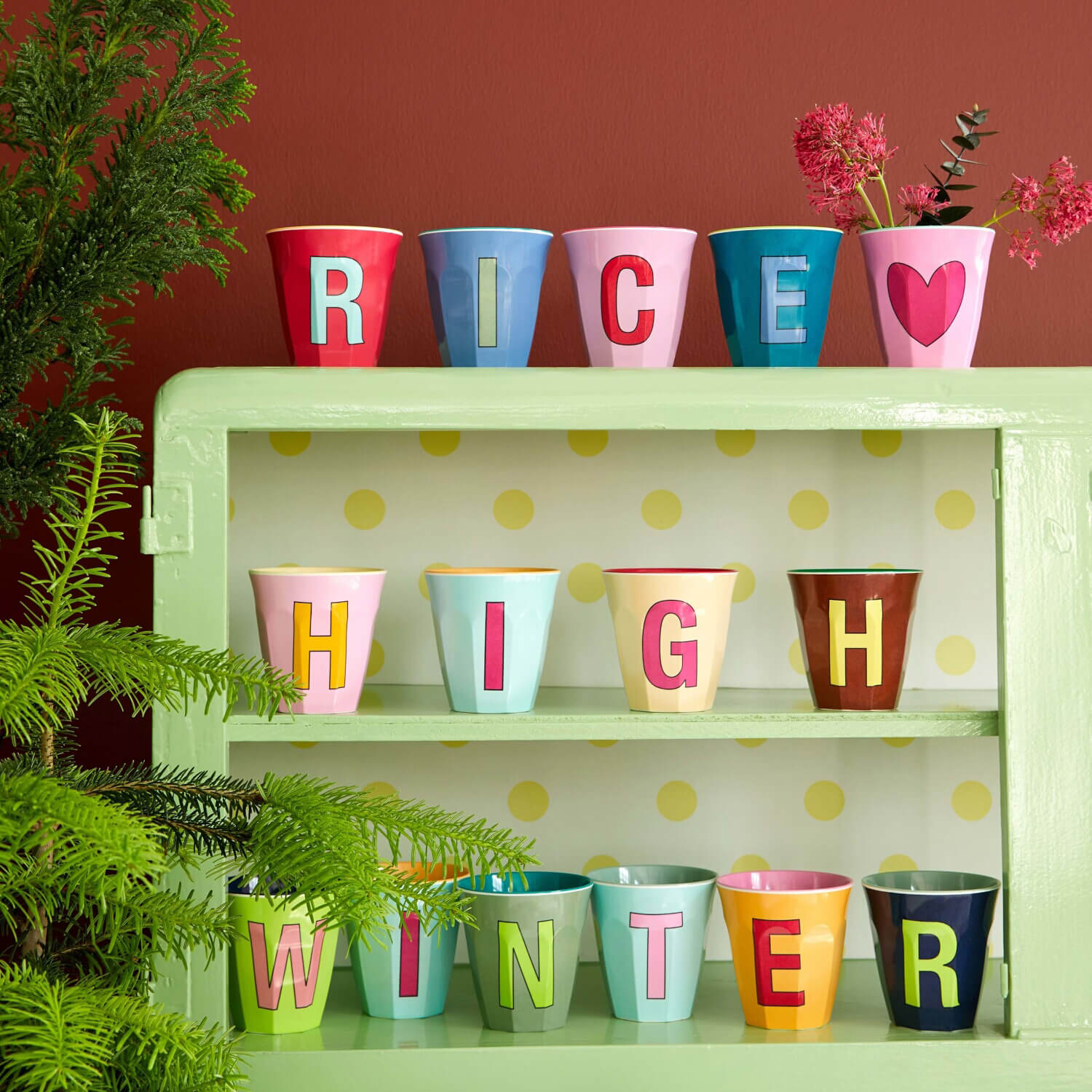 Melaminbecher auf Regal, bunt bedruckt mit Buchstaben und Herz.