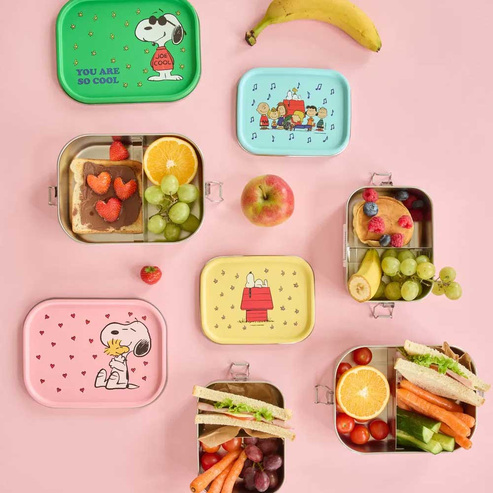 Mehrere Lunchboxen mit Comic-Motiven und Pastellfarben, teils mit Snacks gefüllt