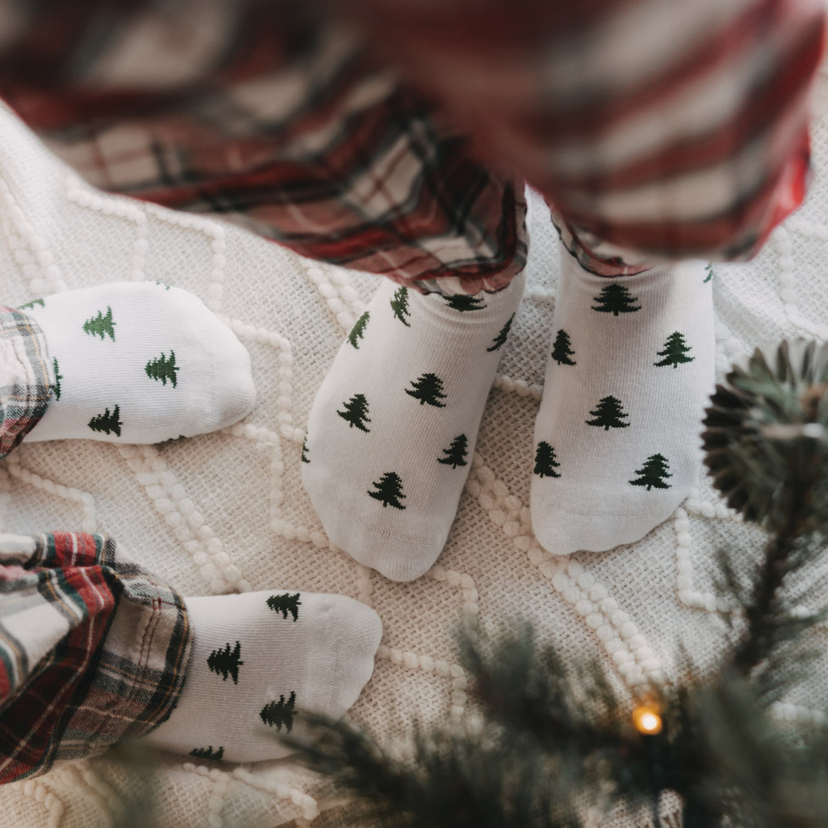 Weiße Socken mit kleinen Tannenmotiven, mehrere Socken im Nahblick