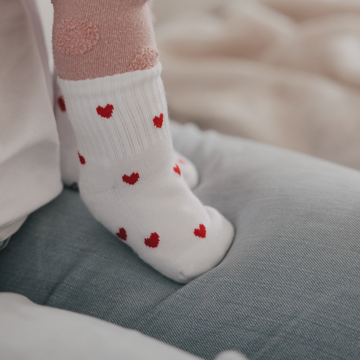 Weiße Babysocken mit roten Herzchen, gerippte Struktur am Knöchel