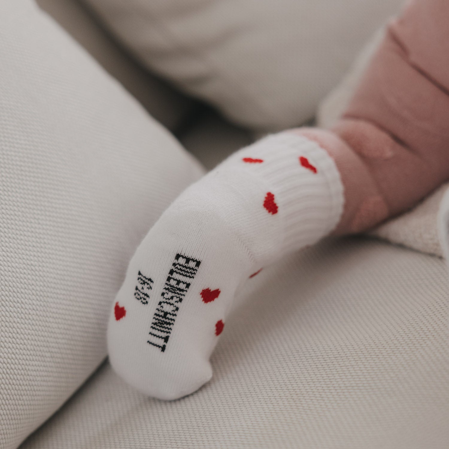 Weiße Babysocke mit roten Herzen und gesticktem Fersenlabel