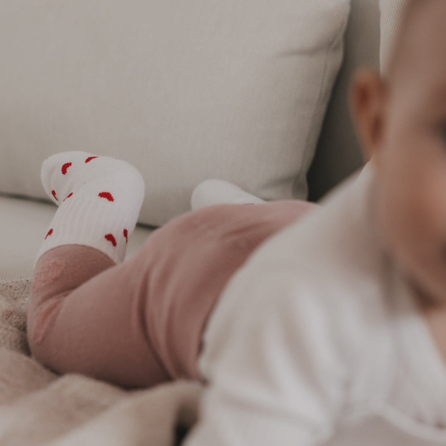 Weiße Babysocken mit roten Herzen am Kinderbein, gerippter Schaft