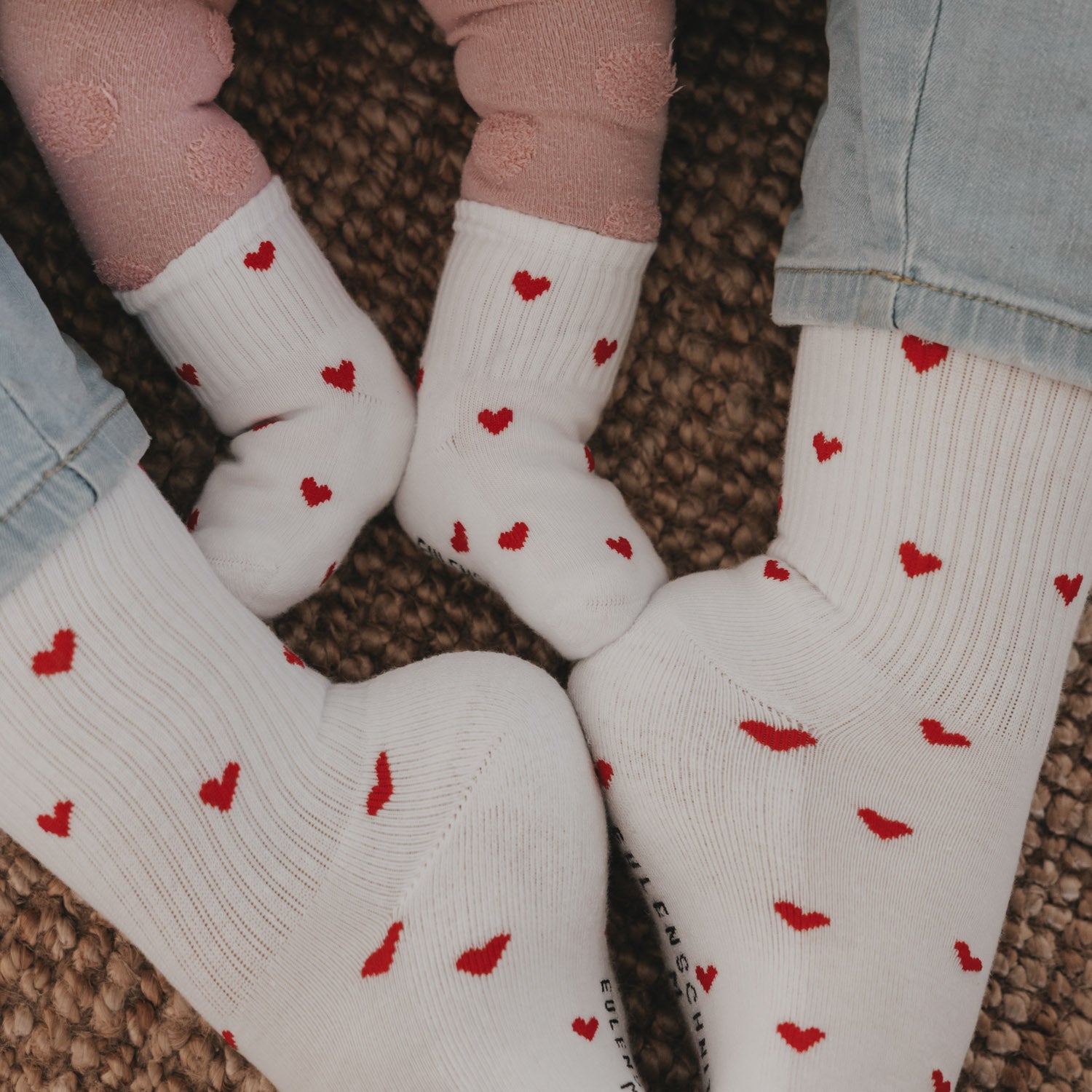 Mehrere weiße Babysocken mit roten Herzen, gerippter Schaft und Fußspitzen