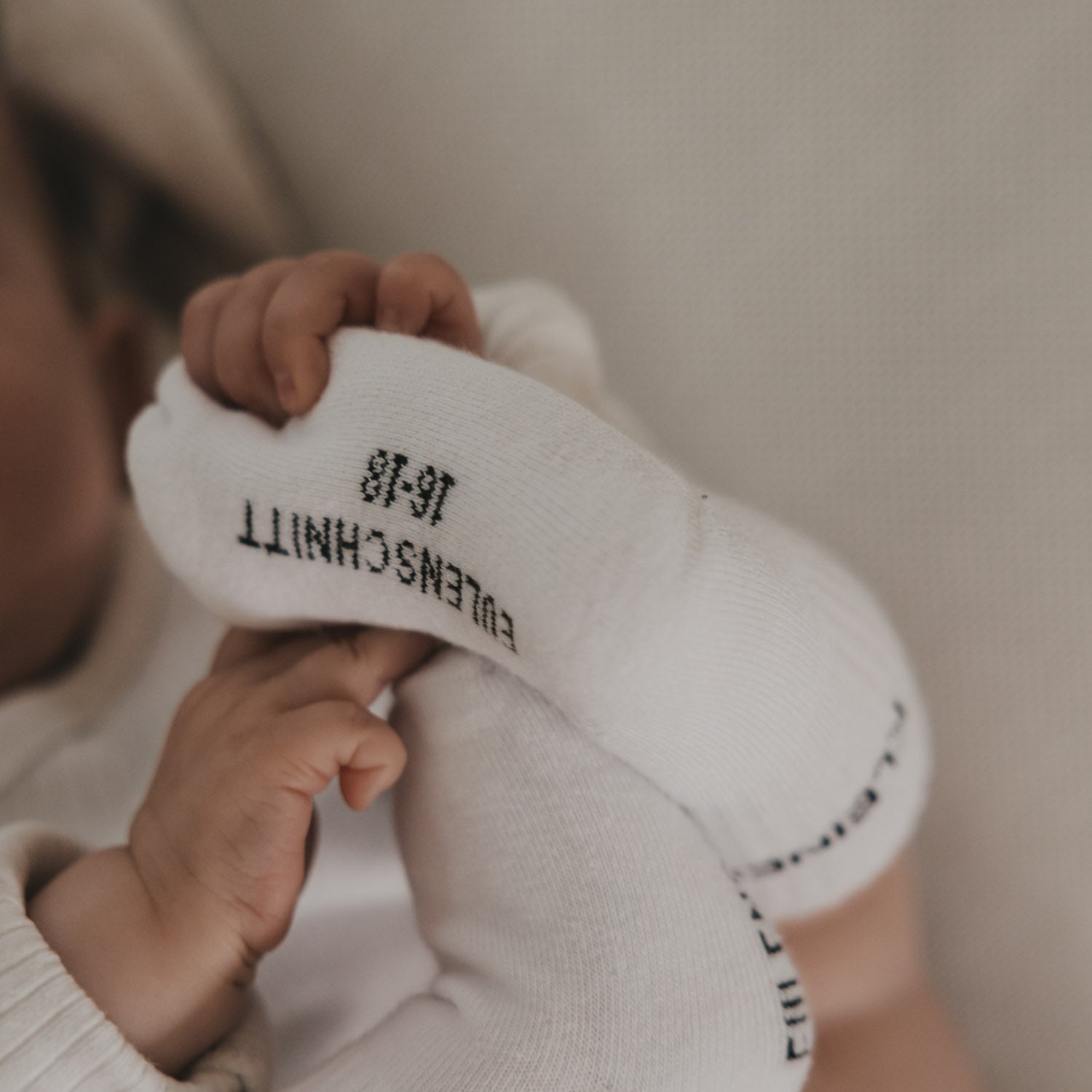 Weiße Babysocke mit Schriftprint innen am Bündchen und weicher Spitze