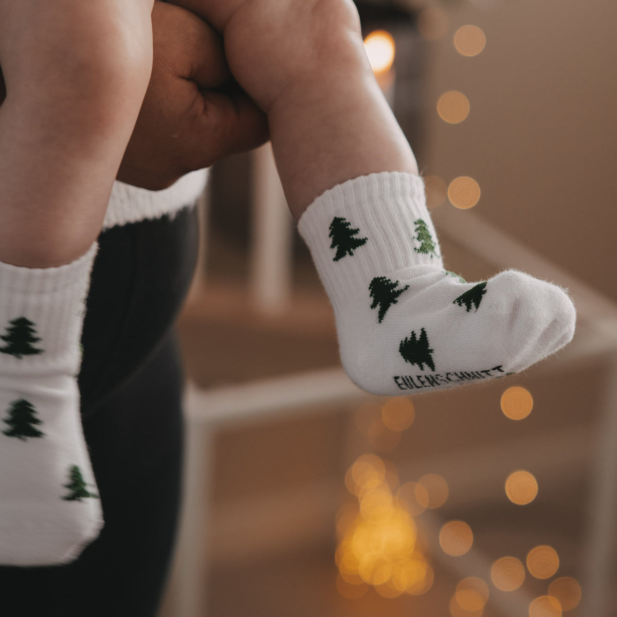 Weiße Babysocke mit grünen Tannen, seitlicher Blick auf das Bündchen
