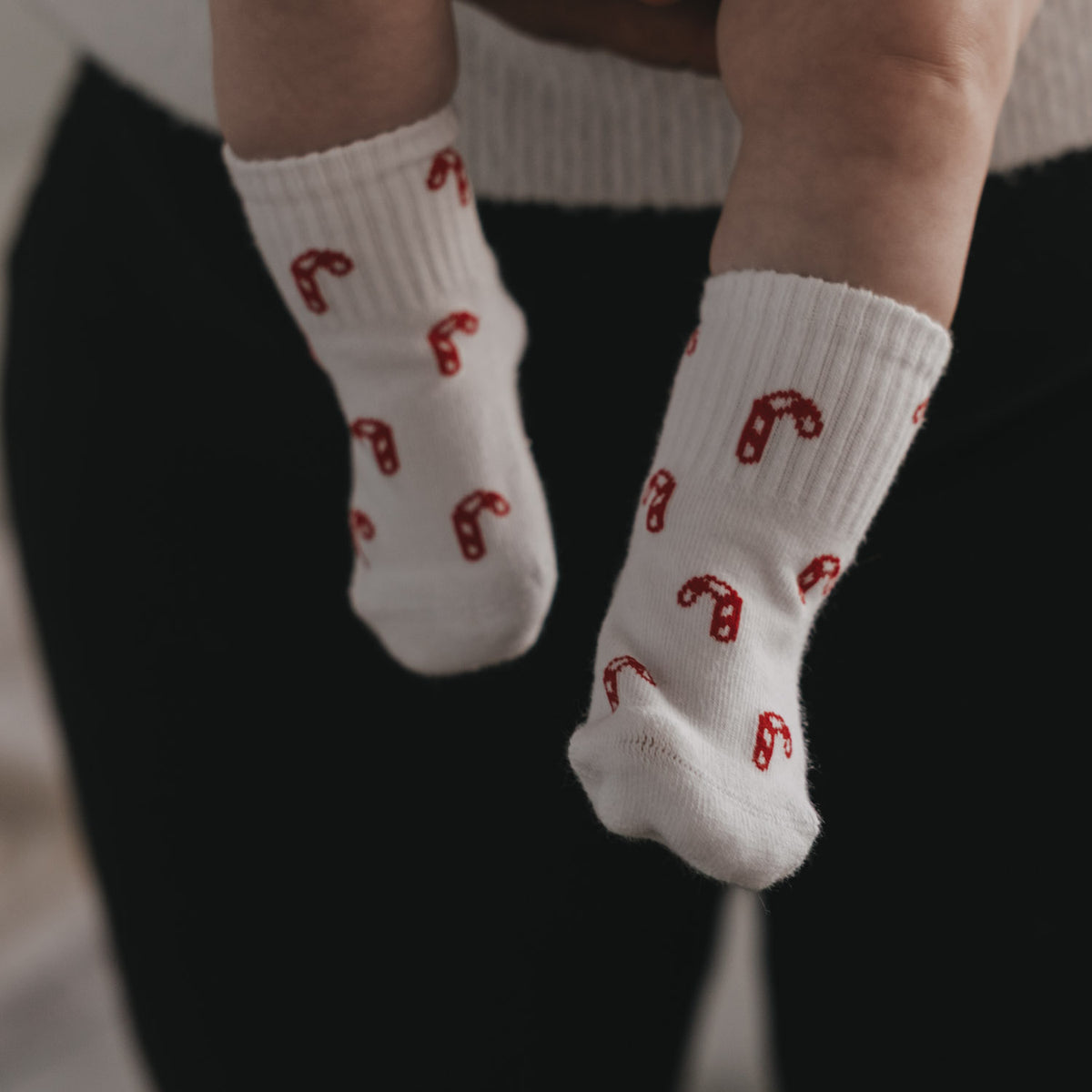 Babysocken in Weiß mit rotem Zuckerstangen-Allover, am Bein getragen