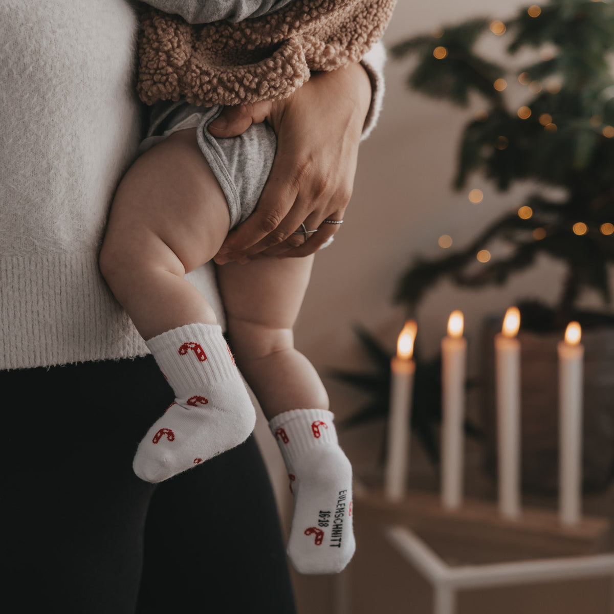 Babysocken in Weiß mit rotem Zuckerstangenprint am Kind, Bündchen sichtbar