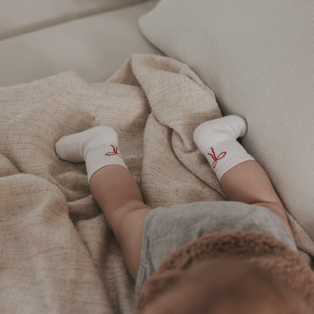 Babysocken in Weiß mit roter Schleife, geripptes Bündchen am Knöchel eines Kindes