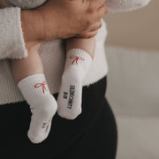 Babysocken in Weiß mit roter Schleife, geripptem Bündchen und Schriftzug am Schaft