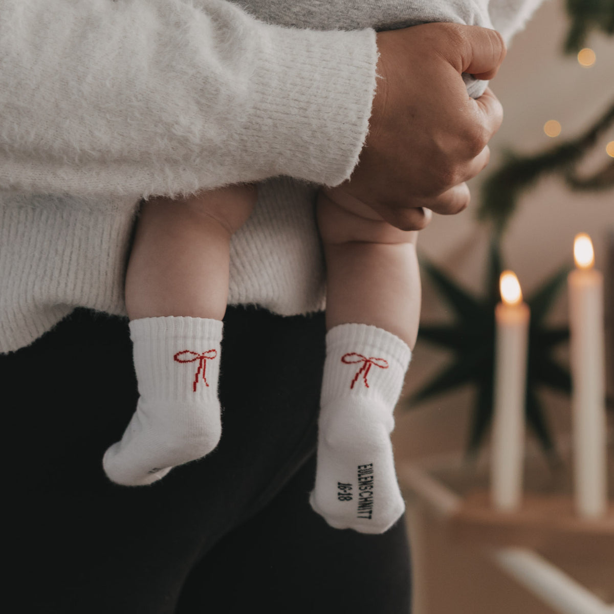 Babysocken in Weiß mit roter Schleife und Schriftzug, Bündchen über dem Knöchel