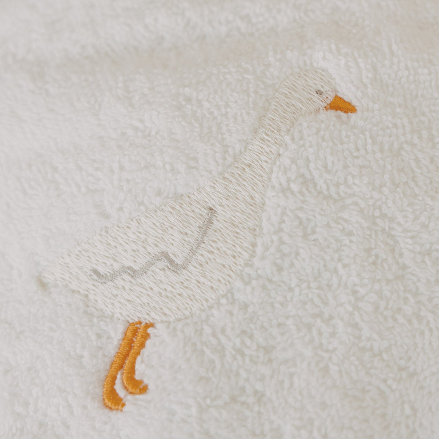 Gansstickerei auf weißem Frottee: kleine Motive in Beige und Orange