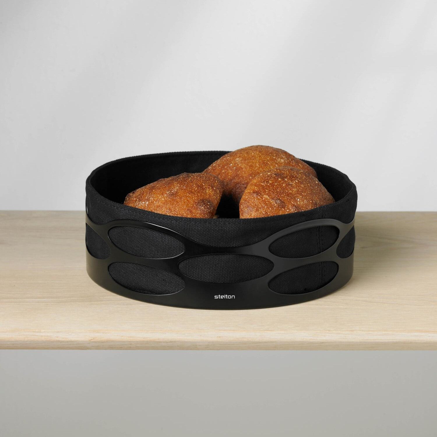 Schwarze Brotschale mit ovalem Muster, gefüllt mit zwei Brötchen