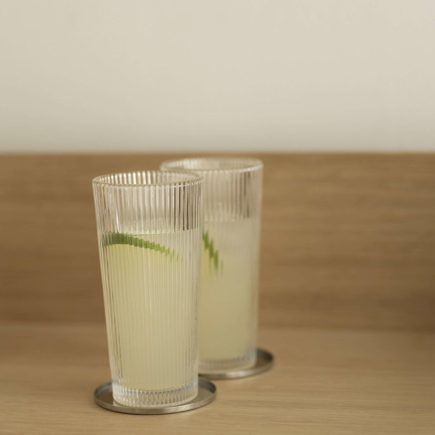 2 transparente Longdrinkgläser mit Riffelstruktur, zylindrisch, mit Getränk