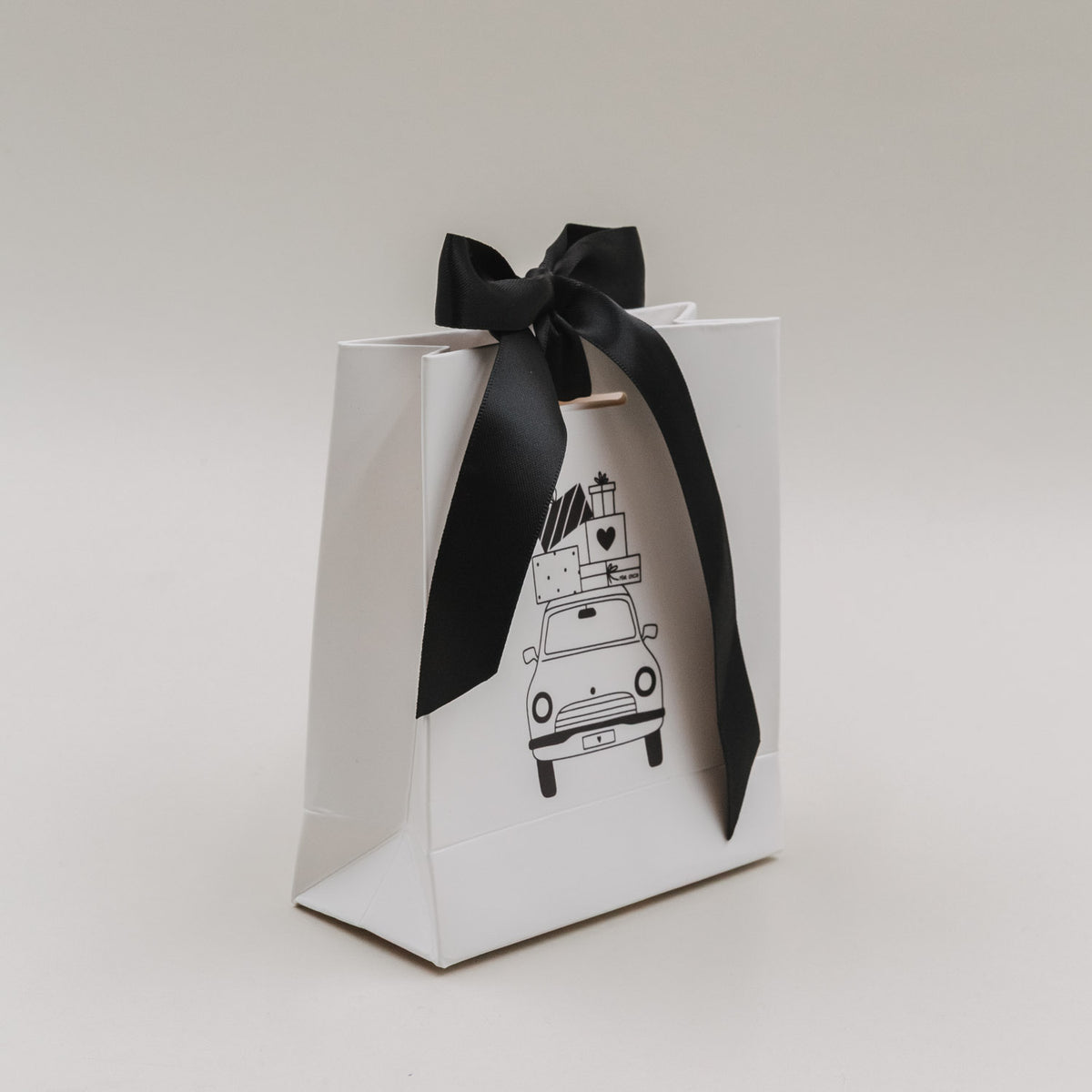Weiße Geschenkbox-Tüte mit schwarzer Schleife und Weihnachtsauto-Illustration, schräg