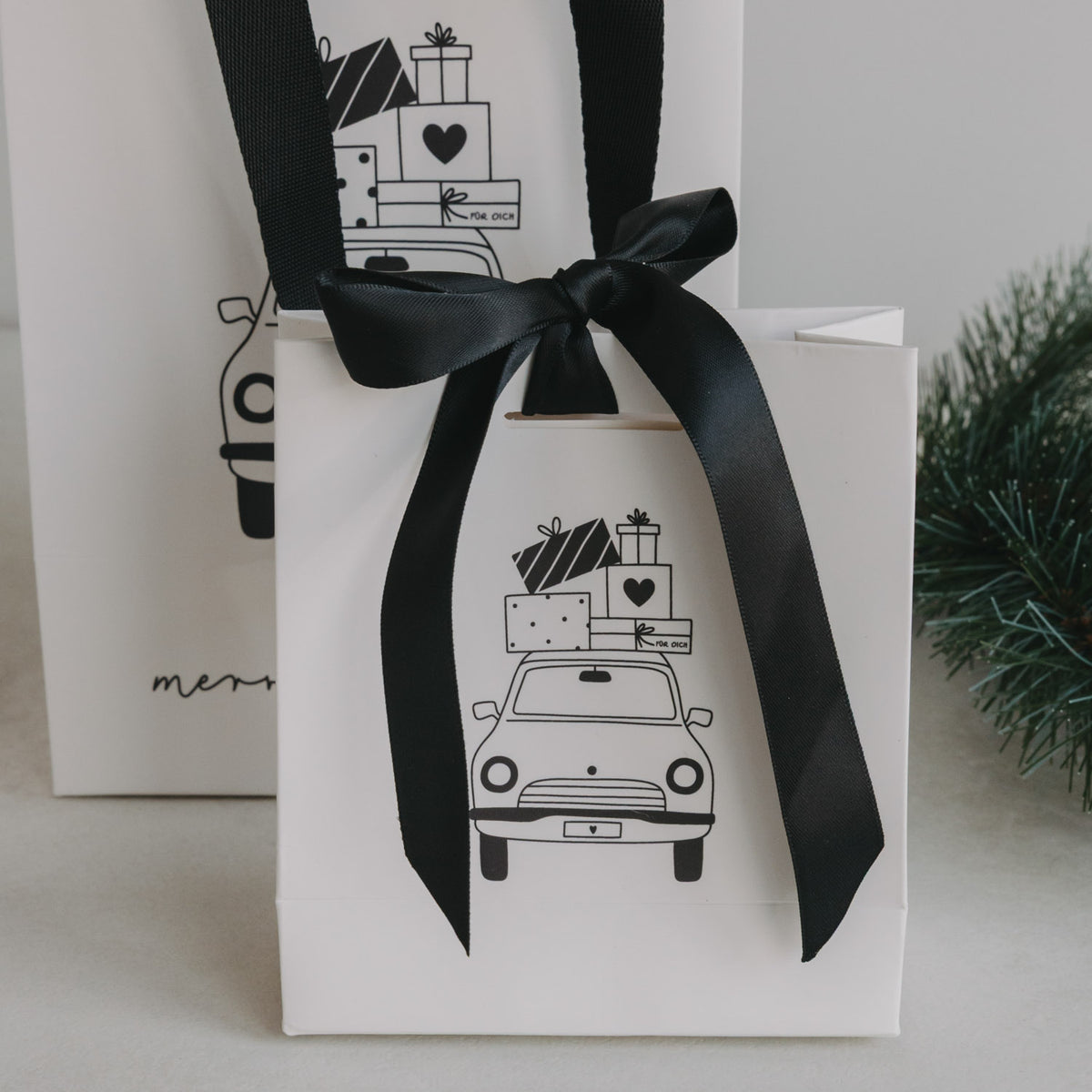 Weiße Geschenktüte mit schwarzer Schleife und Weihnachtsauto-Motiv, Detailansicht